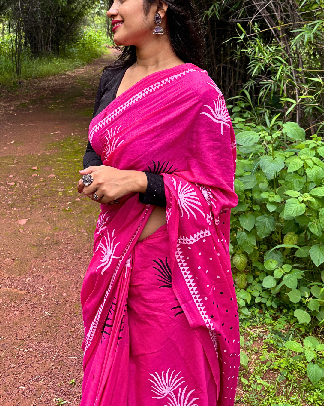 Woman in Pink Saree on Forest Path Woman wearing a bright pink printed saree and black blouse standing on a forest path