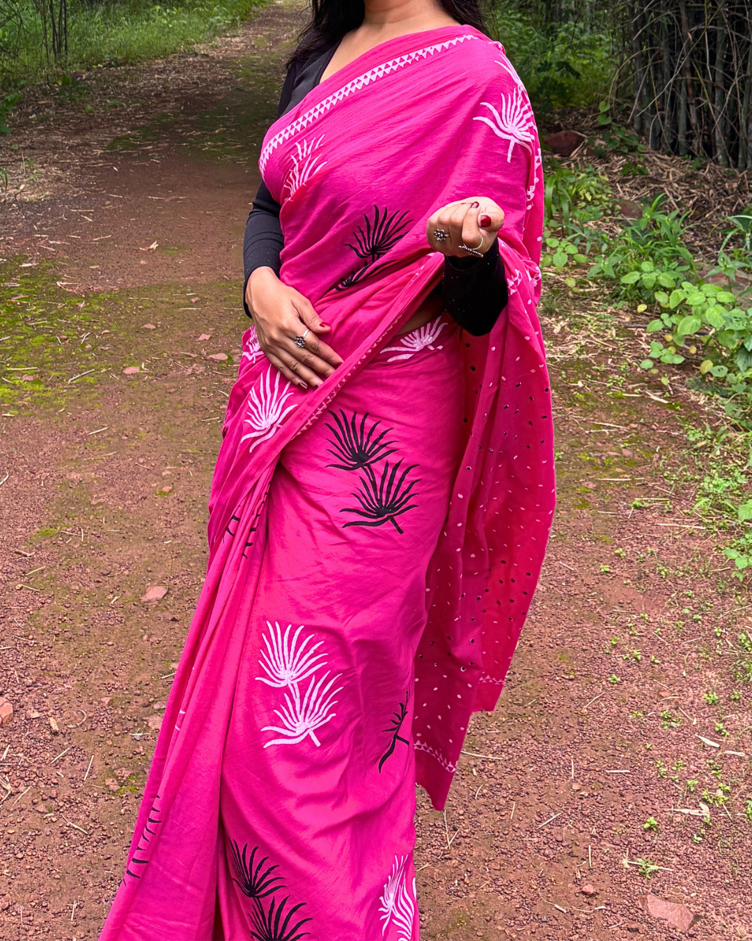Woman Adjusting Pink Saree Woman in a bright pink saree adjusting her saree while standing outdoors